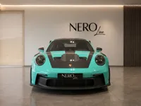 A Gloss Mint Green Porsche 911 GT3 RS is prominently displayed from the front in a modern Zurich showroom.