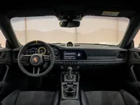 The luxurious black interior of the Porsche 911 GT3 RS in Zurich, featuring its steering wheel, dashboard, and central console.