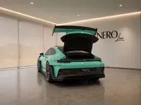 The Gloss Mint Green Porsche 911 GT3 RS is shown from the rear with its engine cover open in a showroom in Zurich.