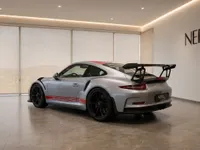 The silver Porsche 911 GT3 RS (991.1) is showcased in a modern Zurich showroom, highlighting its rear three-quarter view and prominent spoiler.