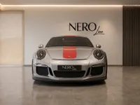 A silver Porsche 911 GT3 RS (991.1) with a distinctive red racing stripe, shown frontally in a modern Zurich showroom.