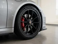 Close-up of the Porsche 911 GT3 RS's front wheel with black rim and red brake calipers in Zurich.