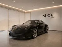 The sleek black Porsche 911 GT3 Touring is showcased in a modern, well-lit NEROline showroom in Lausanne.