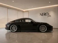 The sleek black Porsche 911 GT3 Touring is showcased in a modern showroom with the NeroLine logo in Lausanne.