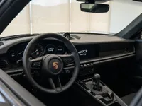The luxurious interior cockpit of the Porsche 911 GT3 Touring in Lausanne, featuring the steering wheel, dashboard, and gear shifter.