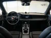 View of the Porsche 911 GT3 Touring's interior cockpit in Lausanne, showcasing the steering wheel, dashboard, and manual gear shifter.