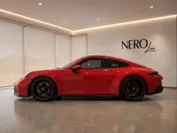 The red Porsche 911 GT3 Touring is showcased in a modern showroom with the Nero Line logo visible on the wall in Zurich.
