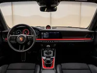 The refined interior of the Porsche 911 GT3 Touring in Zurich, displaying the steering wheel, infotainment screen, and red accents.
