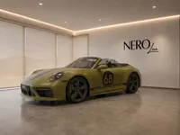 The satin olive green Porsche 911 Spirit 70 convertible is displayed in a modern Zurich showroom, showing its front-three-quarter view.