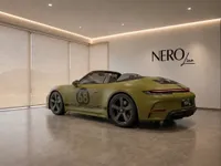 The satin Olive Green Porsche 911 Spirit 70 convertible is displayed from a rear three-quarter view in a modern Zurich showroom.