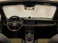The luxurious interior of the Porsche 911 convertible features a detailed dashboard, steering wheel, and unique checkered seats in Zurich.
