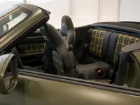 The luxurious interior of the Porsche 911 Spirit 70 convertible in Zurich, showcasing black leather seats with a distinctive yellow plaid pattern.