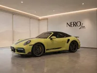 The yellow Porsche 911 Turbo S Cabriolet is showcased from the side in a modern Zurich showroom.