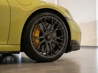 Close-up of the yellow Porsche 911 Turbo S Cabriolet's front wheel with gray multi-spoke rims and yellow brake calipers, in Zurich.