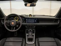 The luxurious black leather interior of the Porsche 911 Turbo S Cabriolet in Zurich, featuring a detailed dashboard, steering wheel, and yellow stitching.