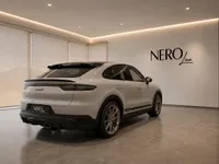 The gloss Chalk Porsche Cayenne Turbo GT is displayed in a modern showroom, viewed from the rear three-quarter angle in Zurich.
