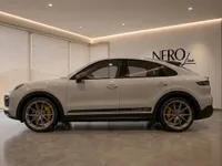 The gloss Chalk 2022 Porsche Cayenne Turbo GT is showcased in a side profile view within a modern Zurich showroom.