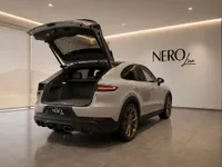 The rear view of a white Porsche Cayenne Turbo GT with its trunk open, showcasing the cargo space inside a showroom in Zurich.
