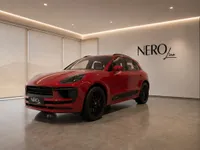 The red Porsche Macan GTS is showcased from a front three-quarter angle in a modern NEROline showroom in Lausanne.