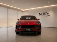 The red Porsche Macan GTS is prominently displayed from the front in a showroom in Lausanne, featuring the NEROline logo.