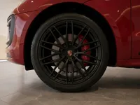 The front wheel of the red Porsche Macan GTS in Lausanne, showcasing black multi-spoke rims and red brake calipers.