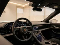 The luxurious interior of the Porsche Taycan Turbo in Lausanne, showing the digital dashboard, steering wheel, and central console.
