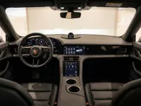 The luxurious interior of the Porsche Taycan Turbo in Lausanne, featuring its advanced digital dashboard, steering wheel, and comfortable black leather seats.