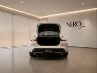 The white Porsche Taycan Turbo is seen from the rear with its trunk open, parked in a showroom in Lausanne.