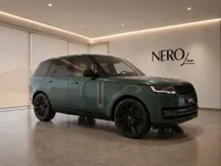 The gloss dark green 2023 Land Rover Range Rover is showcased from a front three-quarter view inside the Nero Line showroom in Lausanne.