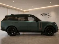 The gloss dark green Land Rover Range Rover HSE is showcased from its side profile in a modern showroom in Lausanne.