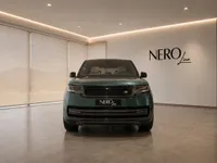The gloss dark green Land Rover Range Rover HSE is prominently displayed from the front in a modern showroom in Lausanne.