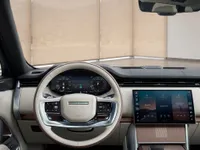 The luxurious cockpit of the 2023 Land Rover Range Rover HSE in Lausanne, featuring a cream steering wheel, digital dashboard, and large infotainment screen.