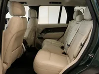 The luxurious rear interior of the Land Rover Range Rover in Lausanne, featuring pristine light beige leather seats and dark green exterior.