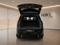 The black Land Rover Range Rover Sport is shown from the rear with its trunk open, parked inside a modern showroom in Lausanne.