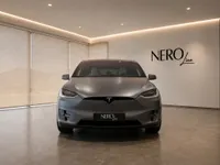 The satin Stealth Grey Tesla Model X is prominently displayed in a modern showroom, showcasing its sleek front design in Lausanne.