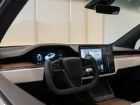 The modern cockpit of the Tesla Model X in Lausanne, featuring the yoke steering wheel and large central display.