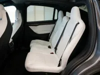 The luxurious interior of the Tesla Model X in Lausanne, showcasing its pristine white leather rear seats and spacious cabin.