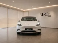 The white Tesla Model Y is prominently displayed head-on in a modern showroom with the NEROline logo in Lausanne.