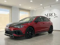 El Volkswagen Golf GTI Clubsport en rojo Kings Red metálico brillante se exhibe desde un ángulo frontal tres cuartos en un moderno concesionario en Alicante.