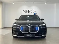 黒いBMW 7プロテクションがマドリードのショールームで正面から展示されており、青い緊急ライトで照らされたグリルとルーフの青いライトバーが特徴です。