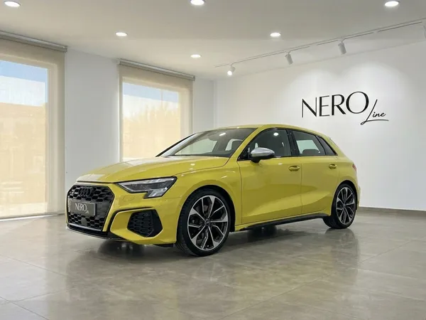 The 2022 Audi S3 in gloss Python Yellow is parked in a modern showroom in Alicante, showcasing its sleek front three-quarter view.