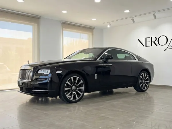 The black 2024 Rolls-Royce Wraith luxury coupe is showcased from a side view in a modern showroom in Malaga.