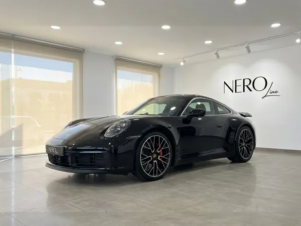 سيارة بورش كاريرا 4S 992.2 كوبيه السوداء الأنيقة معروضة في صالة عرض حديثة بمدريد، مما يبرز تصميمها الديناميكي.