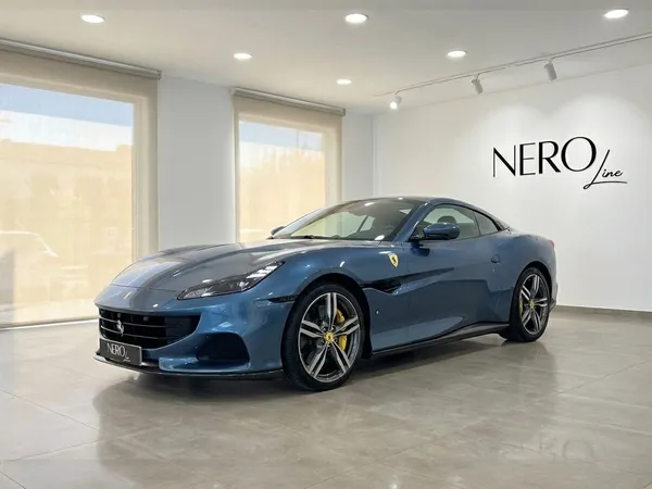 The metallic Blu Roma 2022 Ferrari Portofino M is showcased in a front three-quarter view inside a showroom in Mallorca.