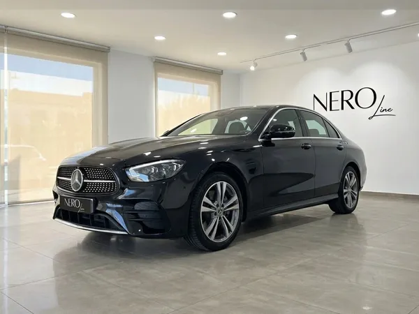 검은색 메르세데스-벤츠 E 300de 럭셔리 세단이 바르셀로나 쇼룸에 주차되어 있으며, 우아한 전면 쿼터 뷰를 보여줍니다.