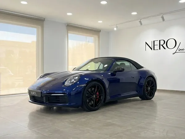 سيارة بورش 911 كاريرا 4S كابريو الزرقاء موديل 2022 متوقفة في الداخل، تعرض تصميمها الأنيق وسقفها القماشي الأسود في إيبيزا.