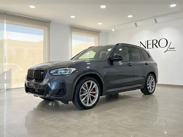 짙은 회색 BMW X3 M50D 럭셔리 퍼포먼스 SUV가 스페인 알리칸테의 쇼룸에서 전면 4분의 3 각도로 전시되어 있습니다.