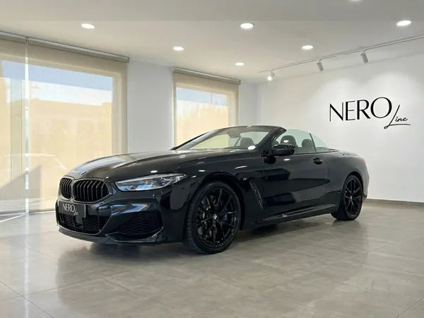 세련된 유광 블랙 2021 BMW M850 컨버터블이 알리칸테의 밝은 쇼룸에서 오픈탑 상태로 전시되어 있으며, 고급스러운 전면 쿼터 뷰를 제공합니다.