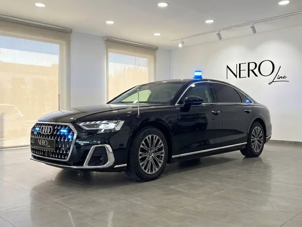 The black Audi A8 L VR10 Armoured car is parked in a modern showroom in Madrid, featuring a blue emergency light on its roof.