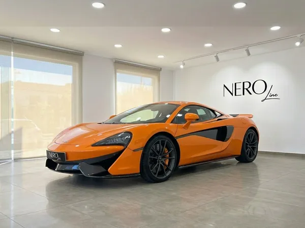 マクラーレン 570S スパイダー — マドリードのショールーム オレンジ色のマクラーレン570Sスパイダーがマドリードのショールームに駐車されており、前方3/4の角度から撮影されています。
